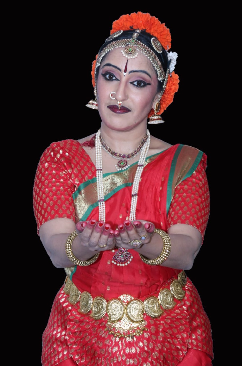 A Bharatanatyam dancer in red costume with hands in a mudra