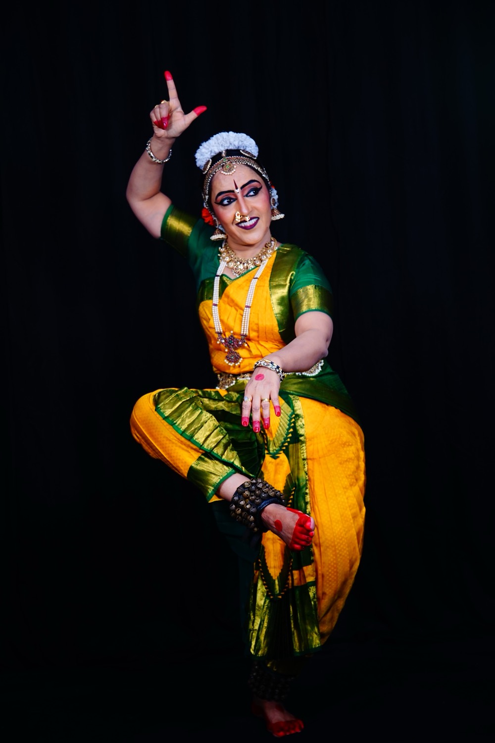 Vidushi Mithra Naveen in a Bharatanatyam pose, in green and gold costume